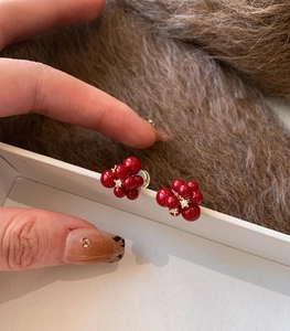 Macro detail of red resin flower stud earrings with sparkling central zircon accents