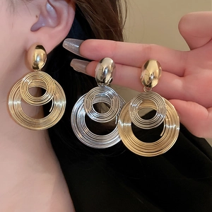 Gros plan sur des boucles d'oreilles géométriques multicouches en finitions or et argent