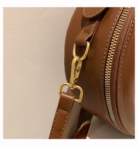 Dettaglio della borsa circolare marrone con trama in pelle liscia e finiture dorate