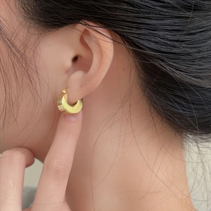 Polished gold U-shaped hoop earrings on model featuring minimalist wide curved design