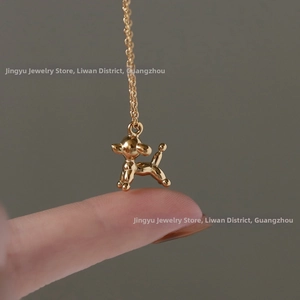 Macro shot of a polished 18K gold-plated balloon dog pendant on a delicate cable chain