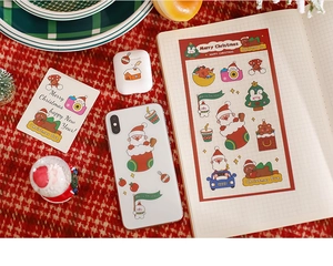 Detailed view of festive Christmas PET stickers applied on phone case and notebook