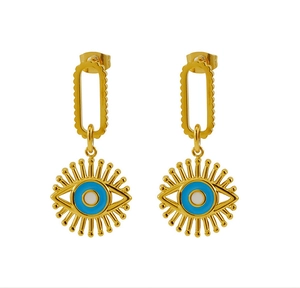 Detailed macro of golden Evil Eye drop earrings with blue enamel and sunburst lashes