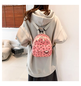 Detail view of pink corduroy mini backpack featuring cherry patterns and canvas straps
