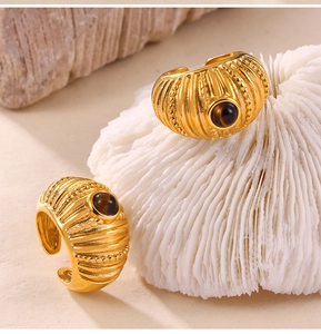 Detailed view of gold plated sea shell texture ring with brown gemstone inlay and coral detail