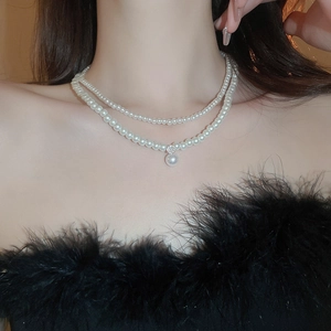 Detail of layered pearl necklace with zircon pendant worn on neck with elegant lighting