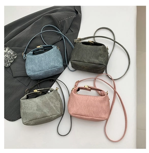 Flat lay of multiple minimalist crossbody bags in matte blue, green, grey, and pink finishes