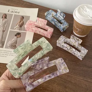 Rectangle marble acetate hair claws with rhinestones in five pastel colors on a wood table