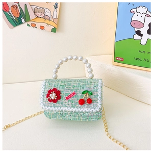 Détail du sac enfant en tweed vert menthe avec poignée perle, accents cerise et chaîne dorée