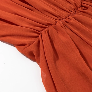 Detail of ruched orange fabric with pleat textures on a V-neck chic dress