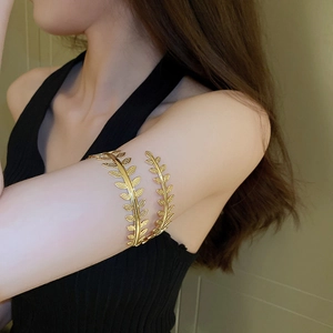Detail of a golden leaf arm cuff bracelet with elegant texture on a female model