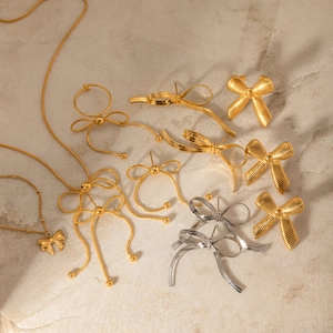 Elegant gold and silver bow-knot necklaces and earrings set on light textured stone