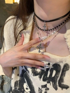 Close-up of layered leather choker and beaded chain with multiple silver cross pendants