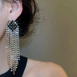 Macro view of silver rhinstone tassel earrings worn by a model with shiny zircon details