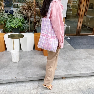 Outdoor street view of a purple checkered canvas bag with 'GROCERY' print list