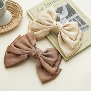 Close-up of layered satin bow hair clips in champagne and brown on a vintage tray