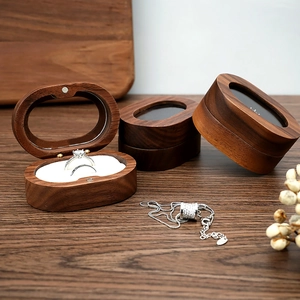 Detail of walnut wood oval jewelry box with clear lid showing rings and necklaces storage