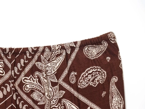 Detail of dark brown trousers featuring white paisley print and elastic waistband