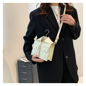 Detail view of a white leather crossbody bag in a creative jacket design with zippers