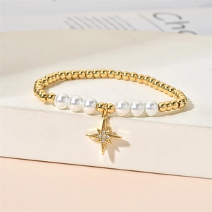 Detail of gold beaded bracelet with white pearls and a sparkling star-shaped pendant