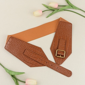Close-up of brown crocodile pattern faux leather belt with a golden buckle on elastic strap