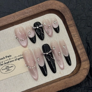 Macro shot of French press-on nails with cat-eye glitter, bow accents, and pearls