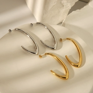 Modern hollow C-shaped gold and silver stainless steel earrings on a white stone base