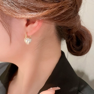 Élégantes boucles d'oreilles créoles cœur en perles dorées portées par un mannequin