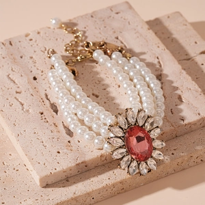 Macro shot of three-strand pearl bracelet with oval red crystal flower center