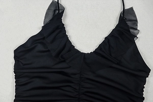 Detail of V-neckline with black mesh ruffles and vertical ruching on a sexy mini dress