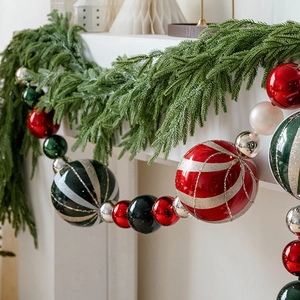 Festive 15cm painted Christmas ball ornaments hanging on a white fireplace mantle
