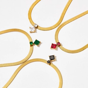 Close-up of golden herringbone necklaces with square colorful stones in a circular layout