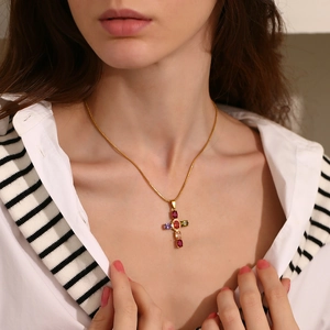 Macro view of 18K gold-plated cross pendant featuring multicolored gemstones and fine chain