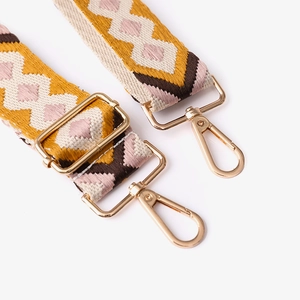 Detail of adjustable ethnic geometric pattern bag straps with gold metal clasps