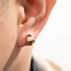 Boucle d'oreille en acier inoxydable doré en forme de paume évidée sur un modèle