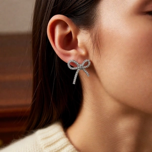 Detail view of a luxury bow-shaped ear cuff with sparkling zircon on a female model