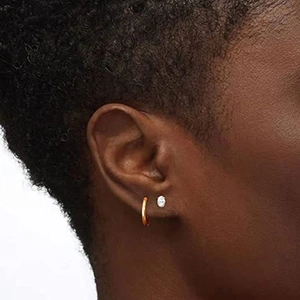 Detail of 925 sterling silver geometric stud earrings and gold hoop on model ear