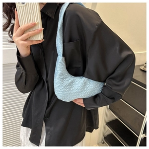 Close-up of light blue croissant bag featuring soft pleated texture and crescent shape