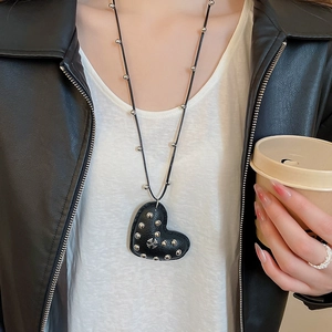 Close-up of leather heart cross pendant necklace with metallic bead details on model