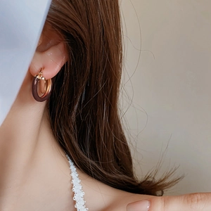 Gros plan de boucles d'oreilles vintage en métal doré avec émail marron sur mannequin