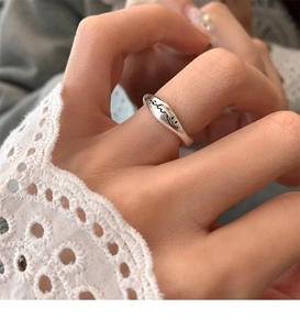 Detail view of silver wavy textured S925 ring on model's hand with white lace cuffs