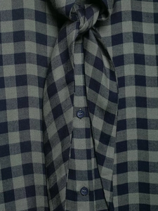 Dettaglio macro del tessuto di una camicia a quadri blu scuro con bottone in resina