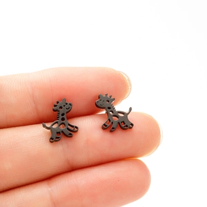 Macro shot of matte black giraffe stud earrings held by hand for size reference