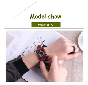 Detail shot of rectangular wood grain watch with Roman numerals and brown leather strap
