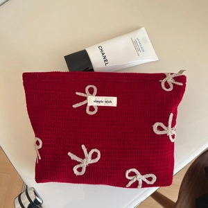 Macro detail of red waffle fabric makeup bag with white bow embroidery and logo