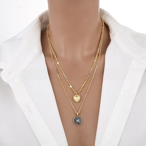 Close-up of double-layer gold necklace featuring heart and star-embossed coin pendants