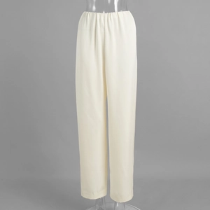 Detail of creamy white satin trousers featuring an elastic waistband and smooth fabric texture