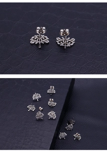 Detail view of silver stainless steel tree of life stud earrings on a black texture