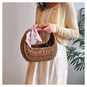 Detail showing a woven brown basket bag with a pink floral scarf held by a model