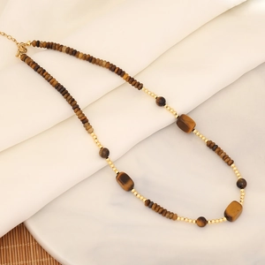 Flat lay of tiger eye beaded necklace with brown stones on white silk and stone tiles